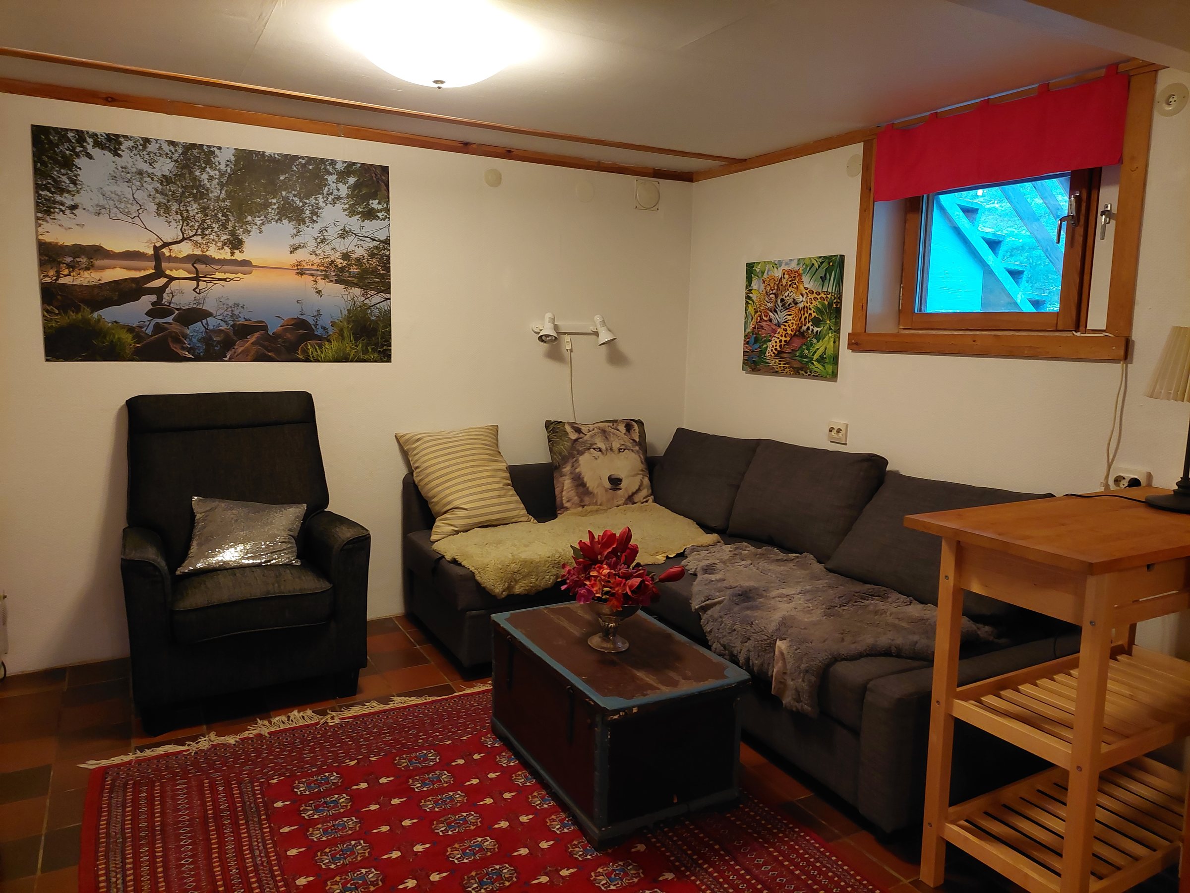 Basement sitting room with sofa, armchair and forest-facing window